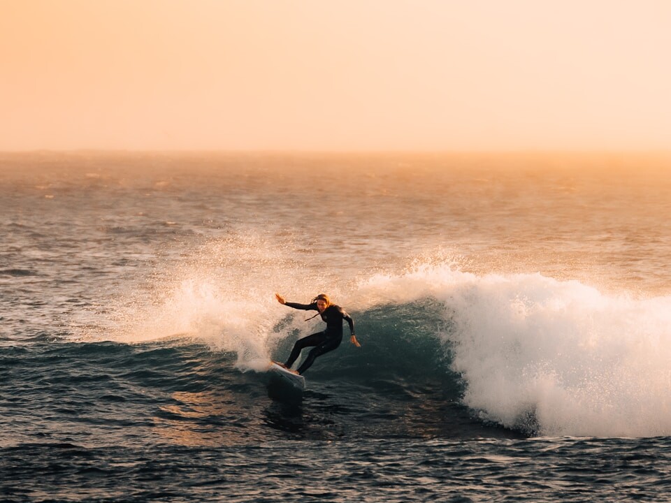 Surfer catching a wave during a beautiful sunset.