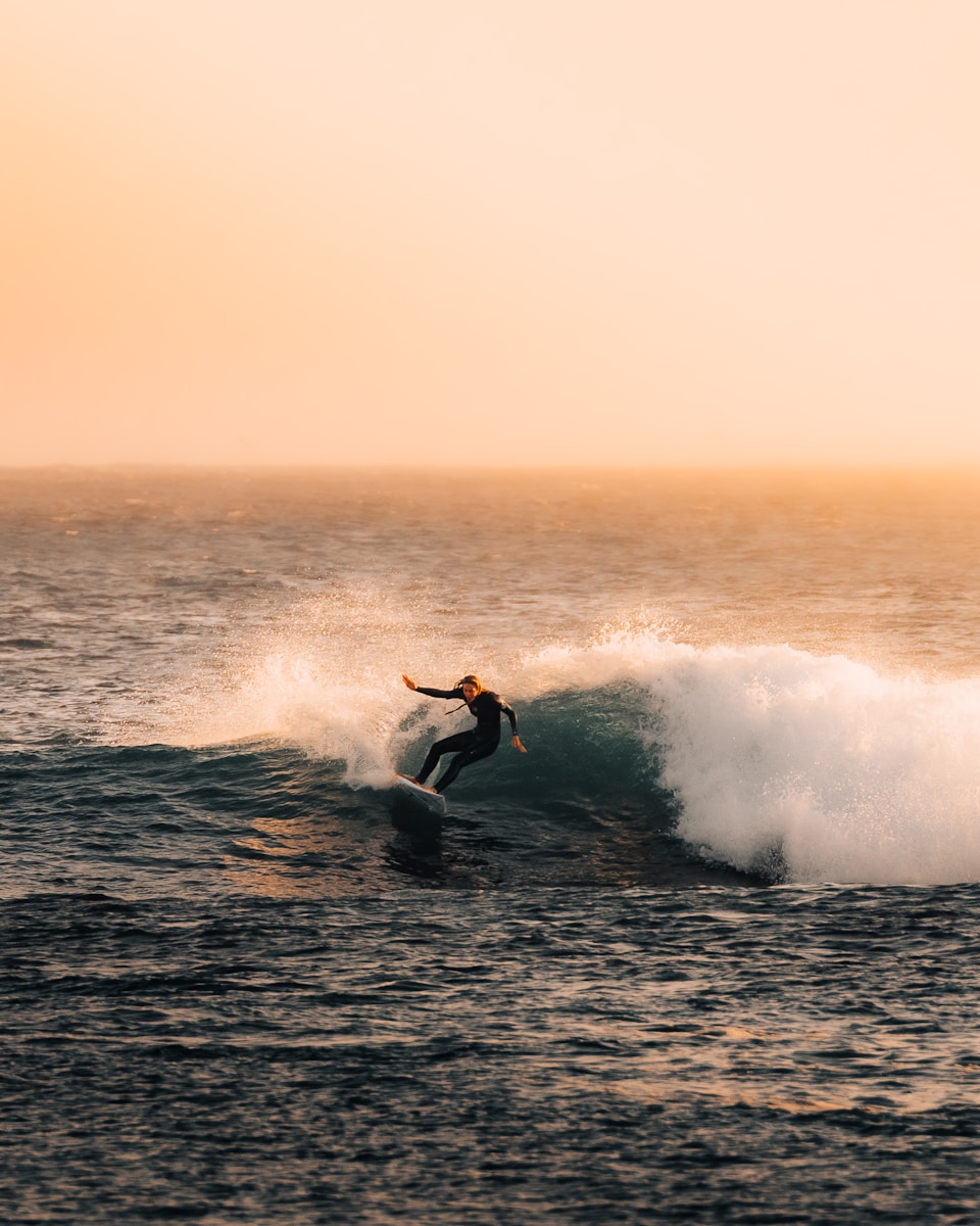 Surfer catching a wave during a beautiful sunset.